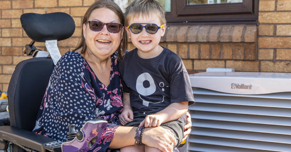 A Mother With Her Son Next To An Air Source Heat Pump