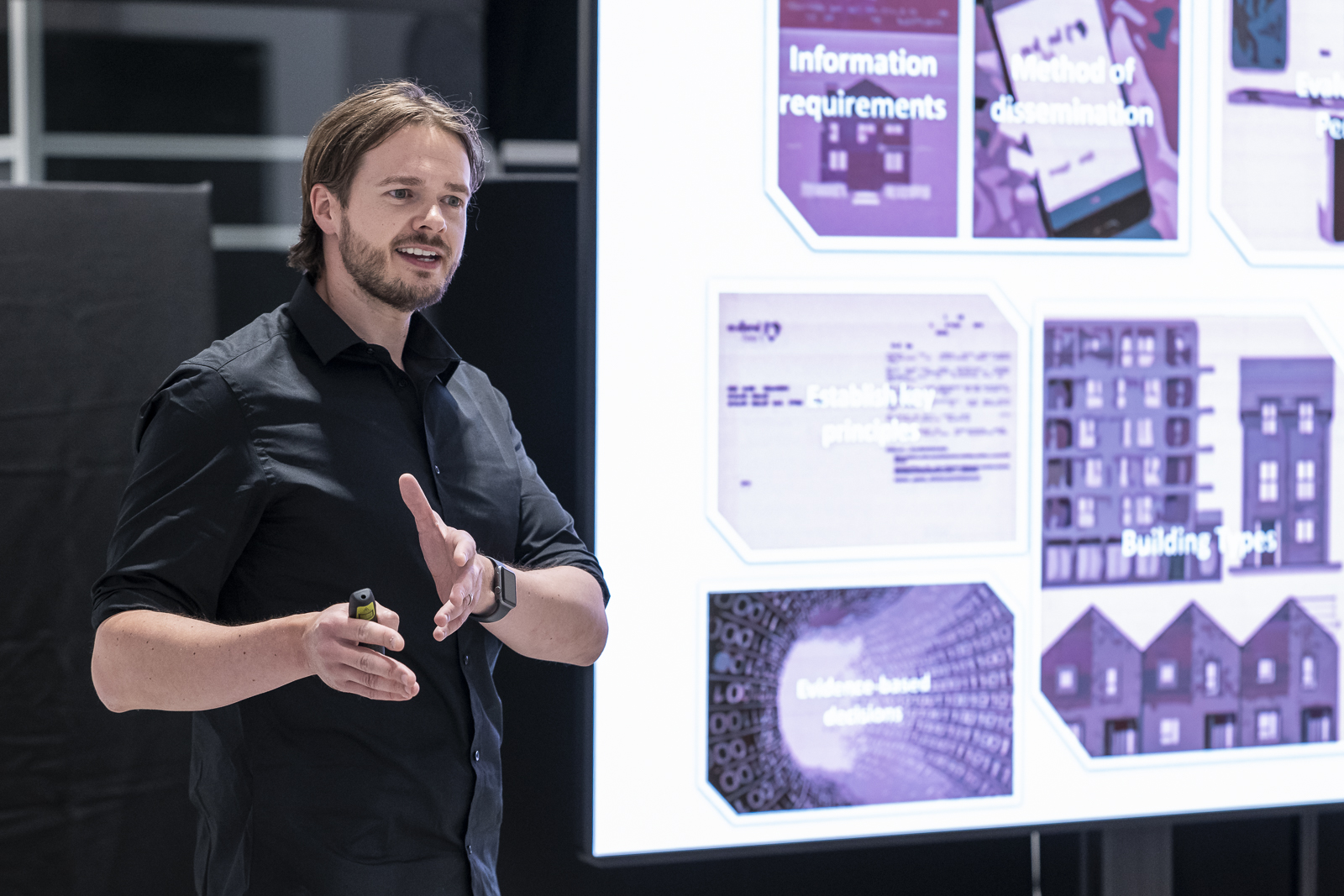 The Head of Construction and Quality speaking about Project 80 next to a big screen with more information