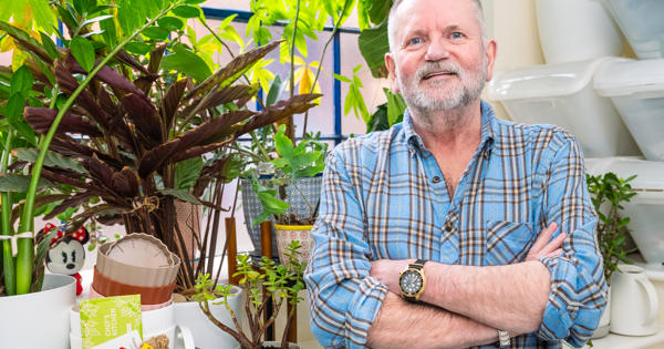 A Man Standing Next To His Indoor House Plants